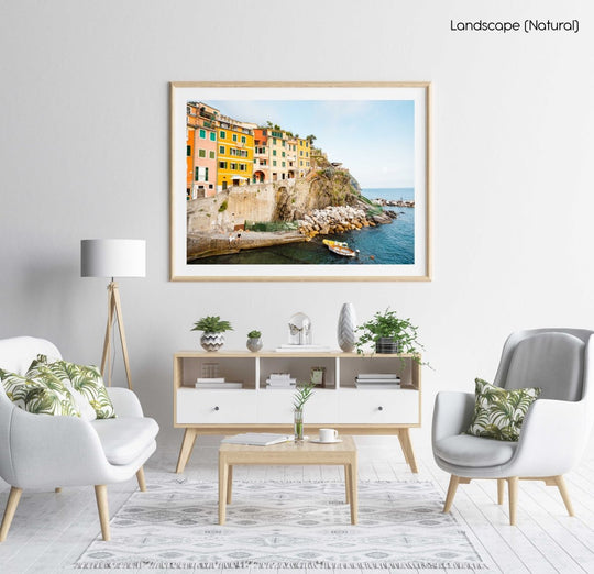 Man and woman sitting alongside docked boats and colorful buildings in Riomaggiore in a natural fine art frame