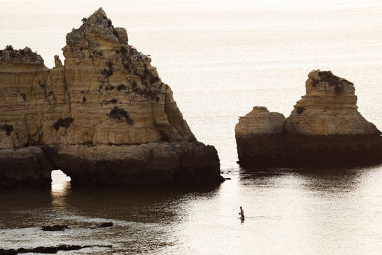 Man swimming during sunrise near large cliffs in Lagos