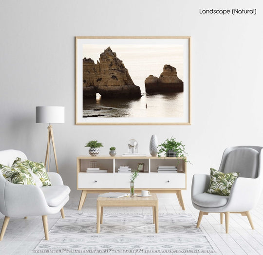 Man swimming during sunrise near large cliffs in Lagos in a natural fine art frame