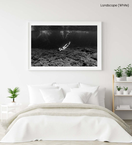 Girl diving underwater along clear coral reef in Bali