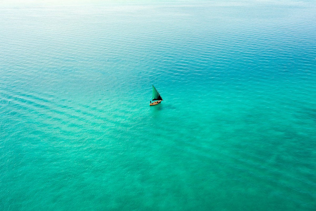 Aerial image taken from a helicopter flight of a dhow boat sailing in bright colourful indian ocean in Bazaruto Archipelago, Mozambique