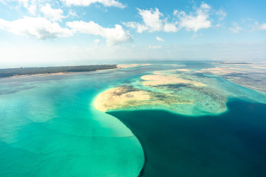 Aerial image taken from scenic helicopter flight of blue shapes of ocean, reef and sand at low tide in Bazaruto Archipelago, Mozambique