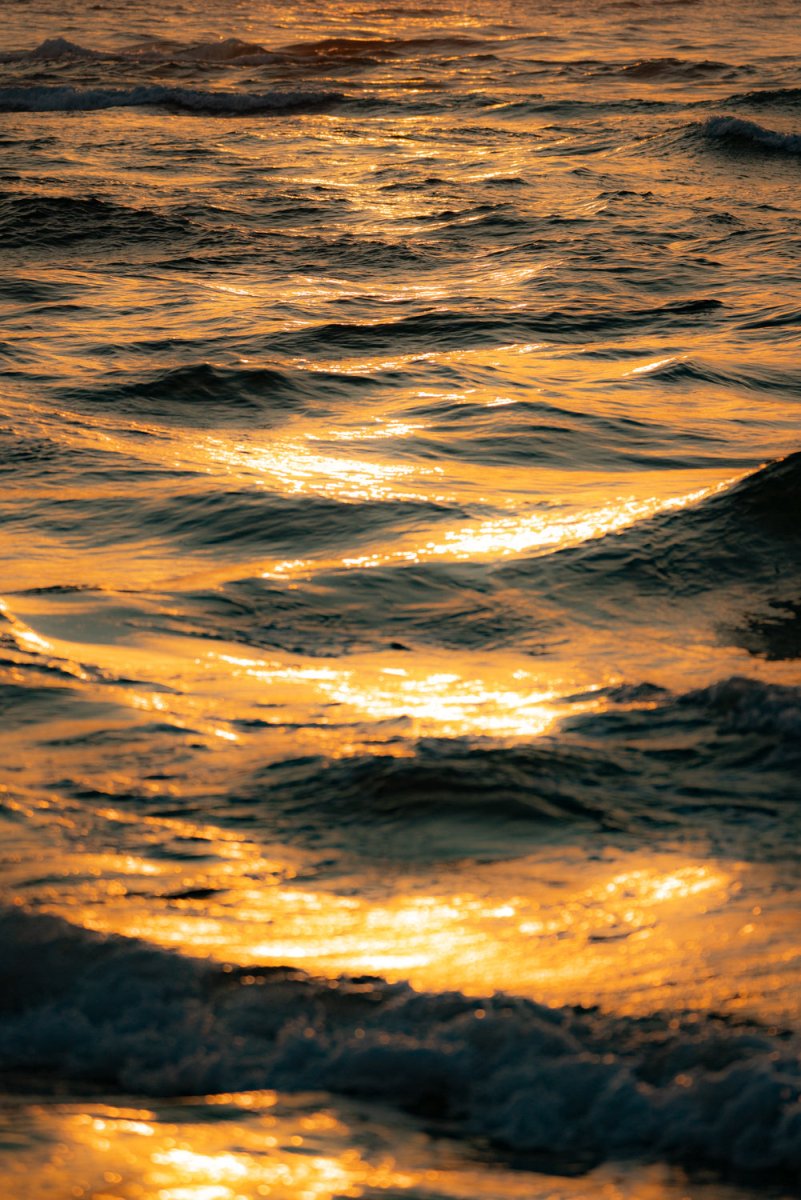 Orange and warm image of ocean ripples and waves during sunrise in Tofo, Mozambique