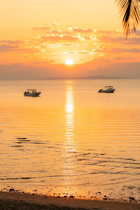 Orange early warm sunrise over the calm water filled with boats in Bazaruto Archipelago, Vilankulos, Mozambique