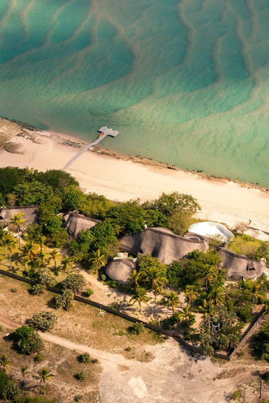 Aerial image of luxury holiday accommodation with palm trees and clear blue ocean along the beach in Bazaruto Archipelago, Vilankulos, Mozambique