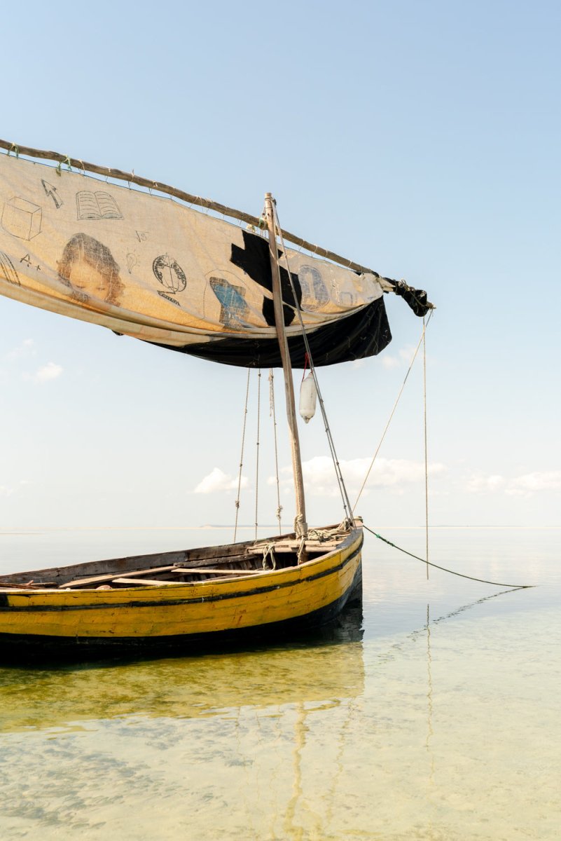 A single dhow is anchored in the shallow water and has childrens drawings on its sail in Bazaruto Archipelago, Vilankulos, Mozambique