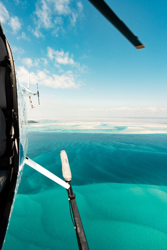 Aerial image captured looking backwards out of helicopter with a backdrop of tropical blue ocean and islands in Bazaruto Archipelago, Vilankulos, Mozambique