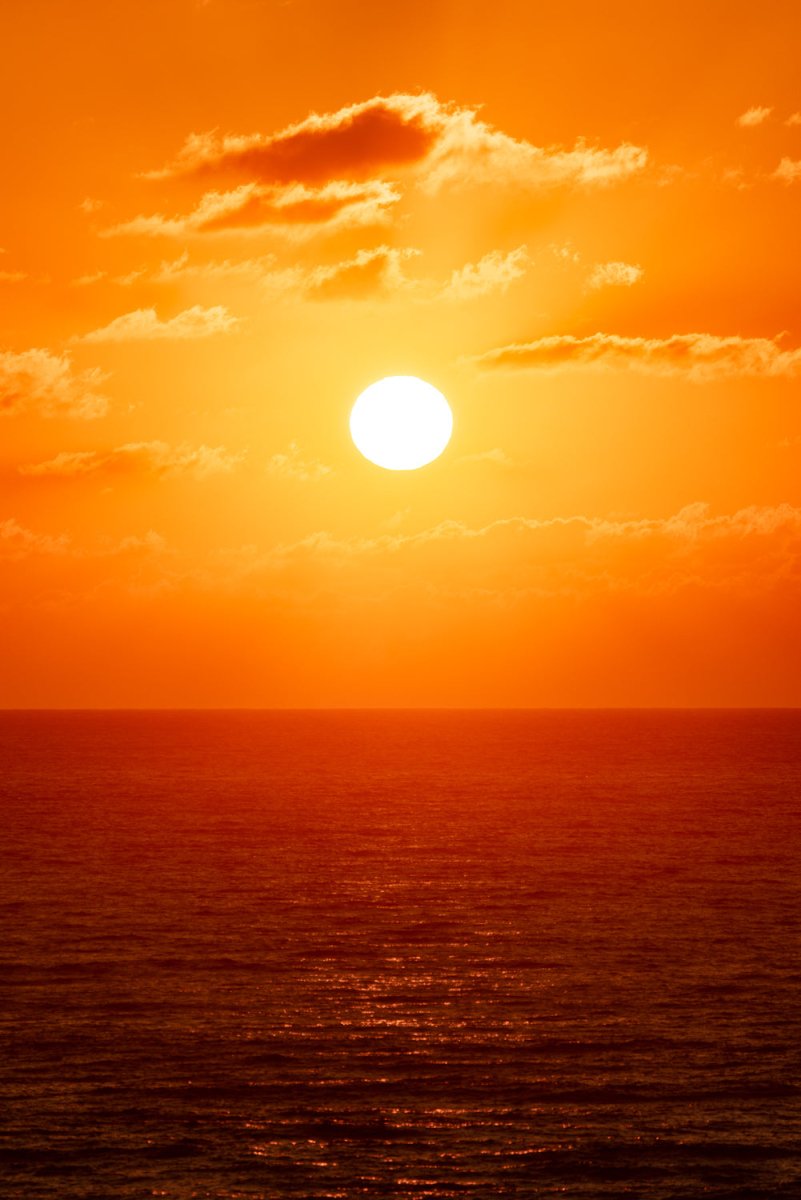 Bright orange and warm image of sun rising over the ocean in Tofo, Mozambique