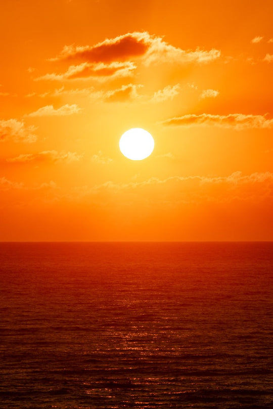 Bright orange and warm image of sun rising over the ocean in Tofo, Mozambique