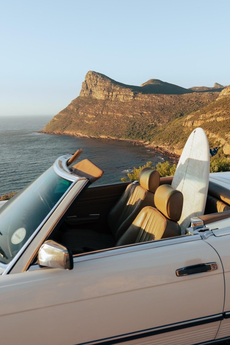 Image of a mercedes parked above Smitswinkel with a surfboard on back seat in Cape Town, South Africa.