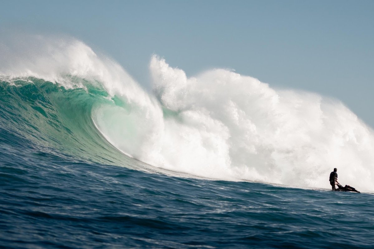 Image of a jetski driving away from big wave crashing at Dungeons wave in Hout Bay, Cape Town, South Africa.