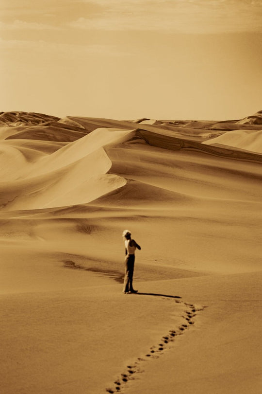 Image of a woman walking on the sandy dunes in swakopmund, Namibia.