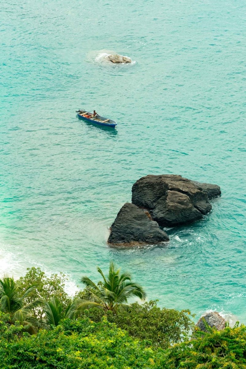 Man sitting in his fishing boat along praia bananas in principe island
