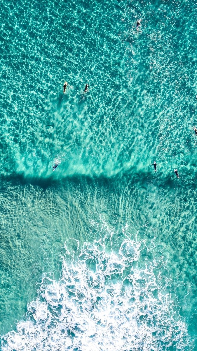 Aerial of Surfers in a turqoise ocean in an acrylic/perspex frame