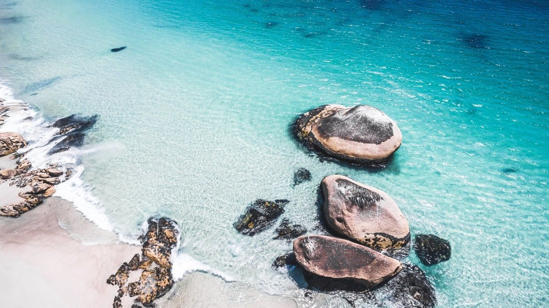 Aerial rocks on clifton beach in clear blue water