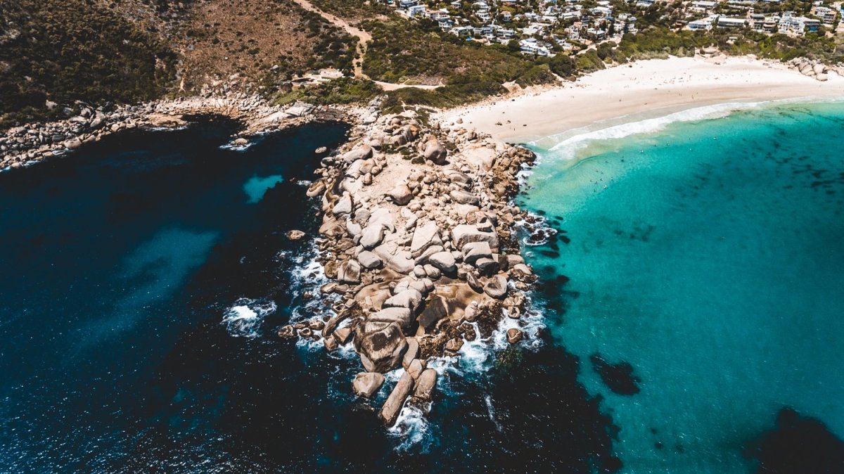 Aerial rocky point with surfers at Llandudno Beach in Cape Town
