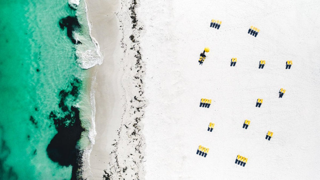 Aerial image of yellow beach chairs on Camps Bay beach Cape Town