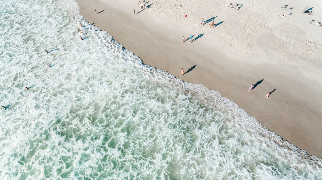 Aerial of swimmers at Llandudno beach in Cape Town during sunset