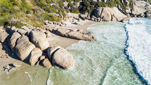 Aerial hightide waves flowing along beach boulders at Llandudno Beach in Cape Town