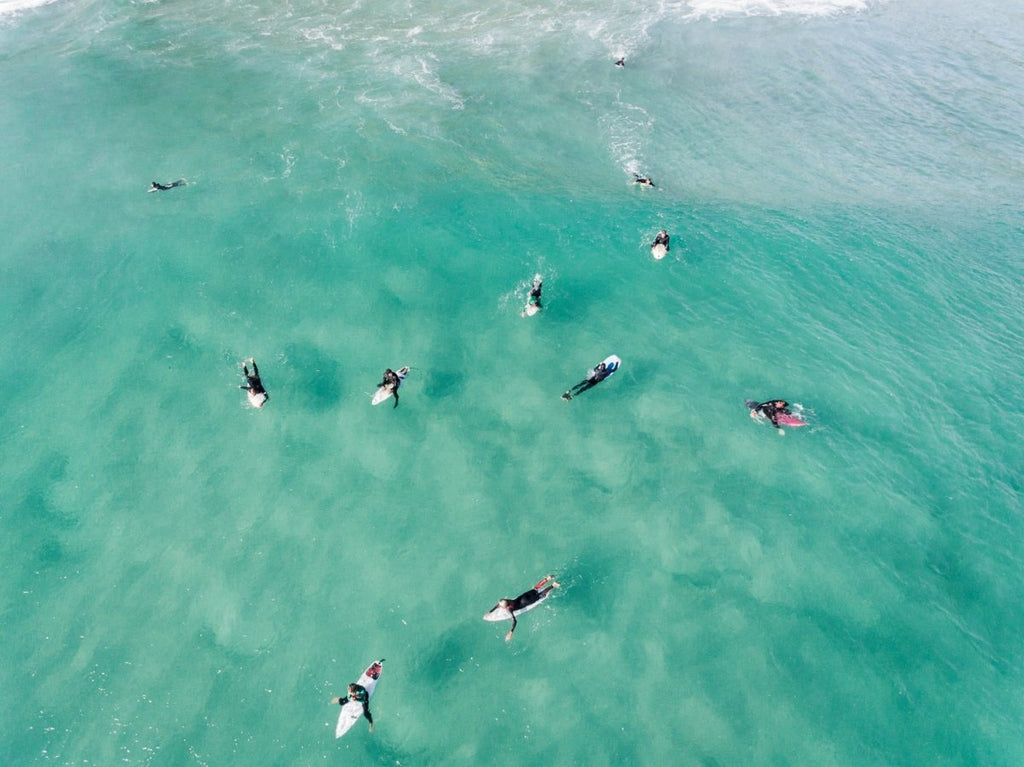 Aerial of surfers waiting and paddling for waves in sea