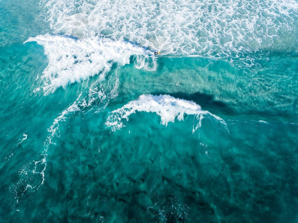 Aerial of two waves breaking in blue ocean in Cape Town