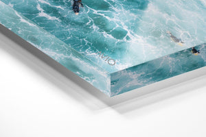 Aerial of two surfers paddling in foamy waves in an acrylic/perspex frame