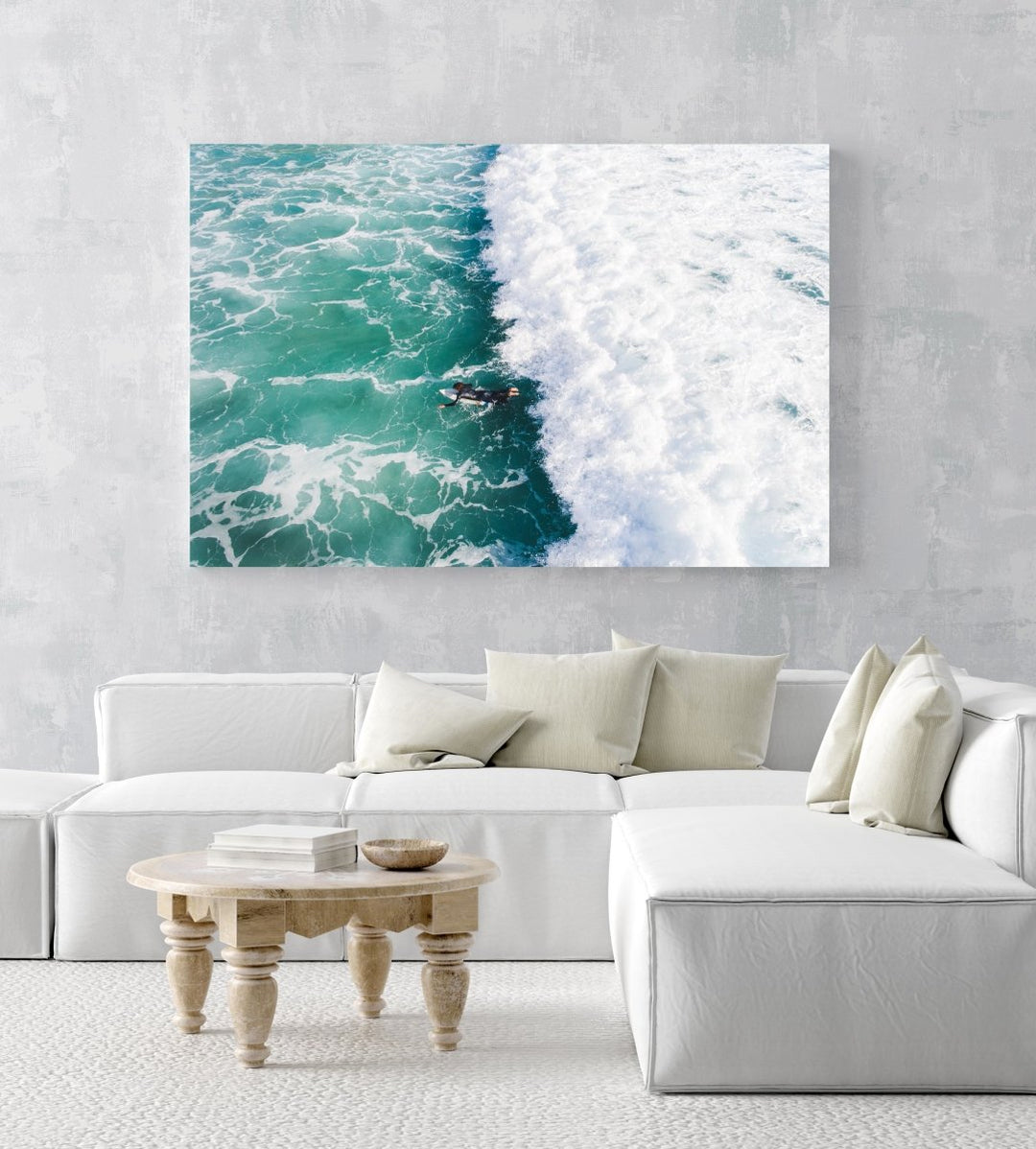 Aerial of one surfer paddling in on a foamy to Llandudno Beach in an acrylic/perspex frame