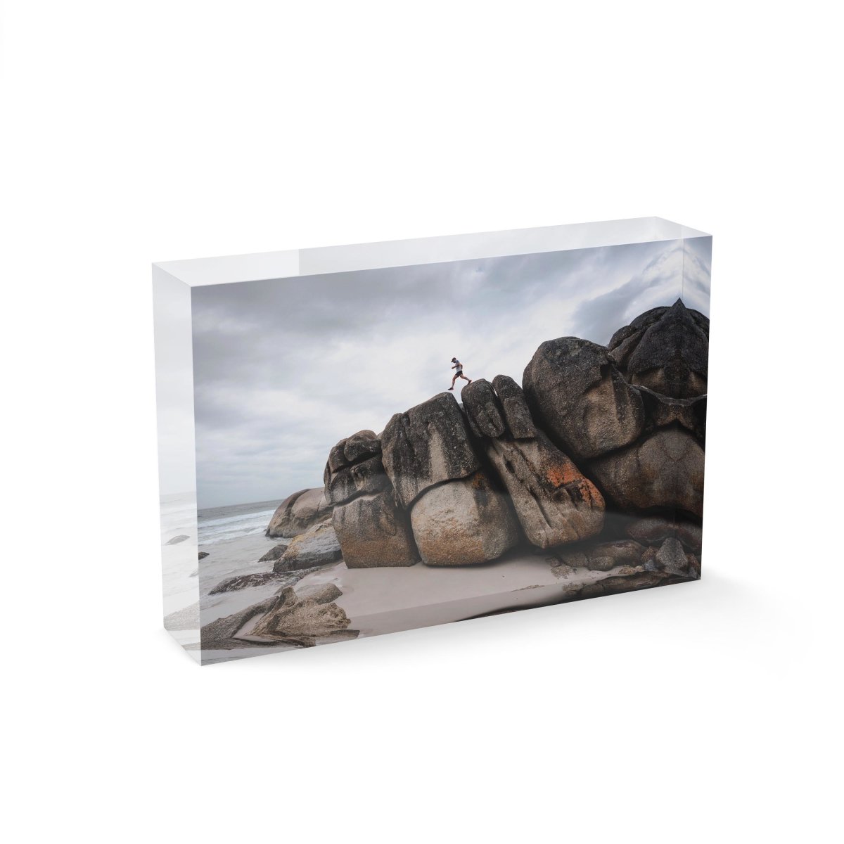 Man walking along high dark boulders on Cape Town beach