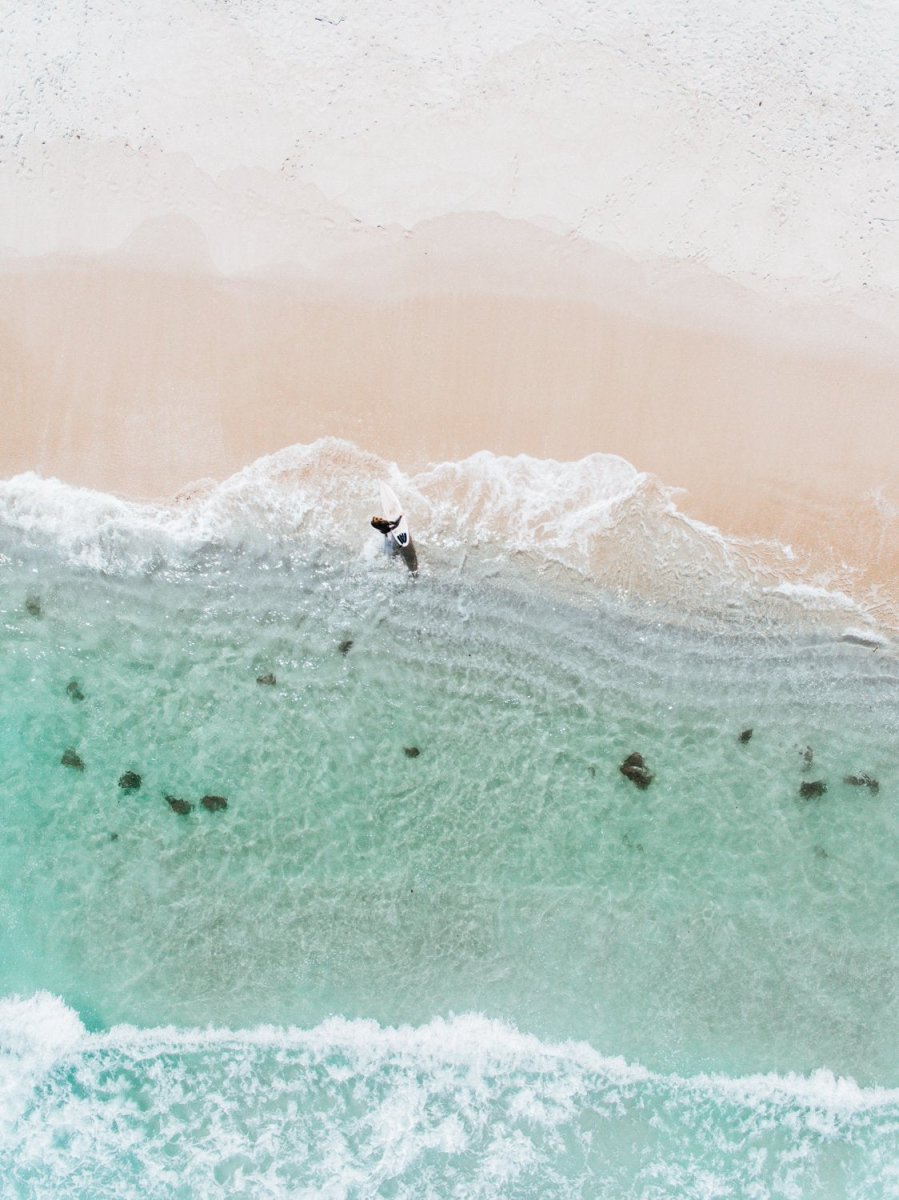 Aerial topdown of surfer walking out of water in Cape Town