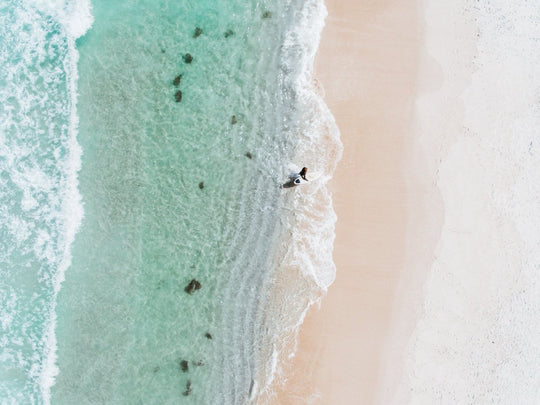 Aerial topdown of surfer walking out of water in Cape Town