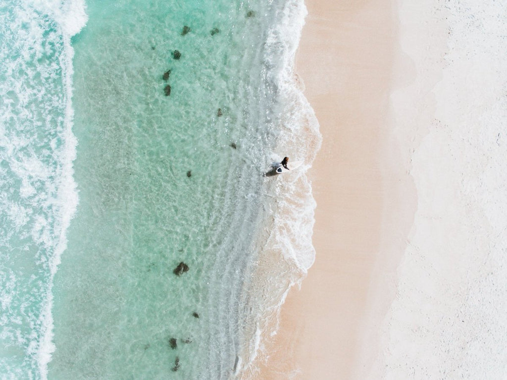 Aerial topdown of surfer walking out of water in Cape Town