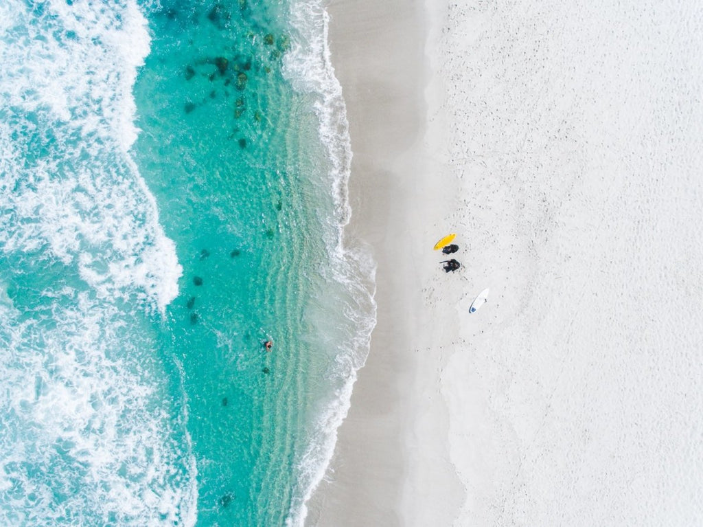 Aerial of two surfers sitting on Glen Beach in Cape Town