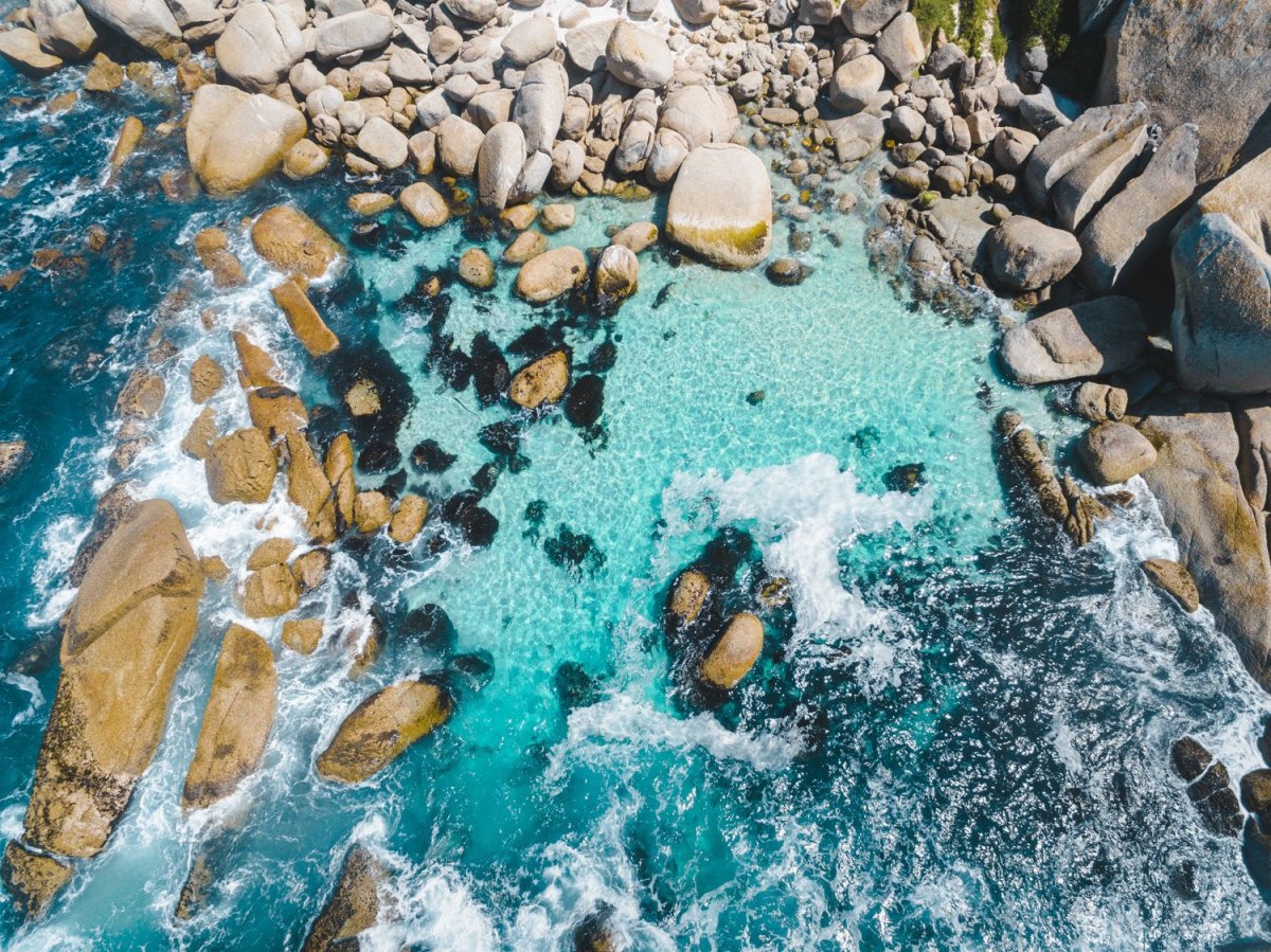 Aerial of blue water and rocks along Camps Bay in Cape Town