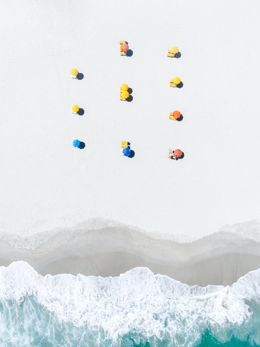 Aerial of colorful umbrellas aligned on camps bay beach in cape town