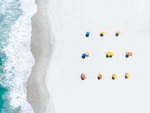 Aerial of colorful umbrellas aligned on camps bay beach in cape town