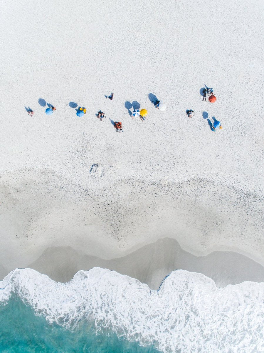 Aerial row of umbrellas on camps bay beach at waves in cape town