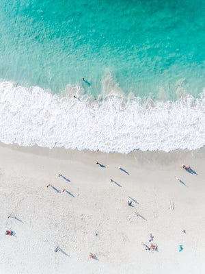 Aerial of green ocean at camps bay beach with people in cape town