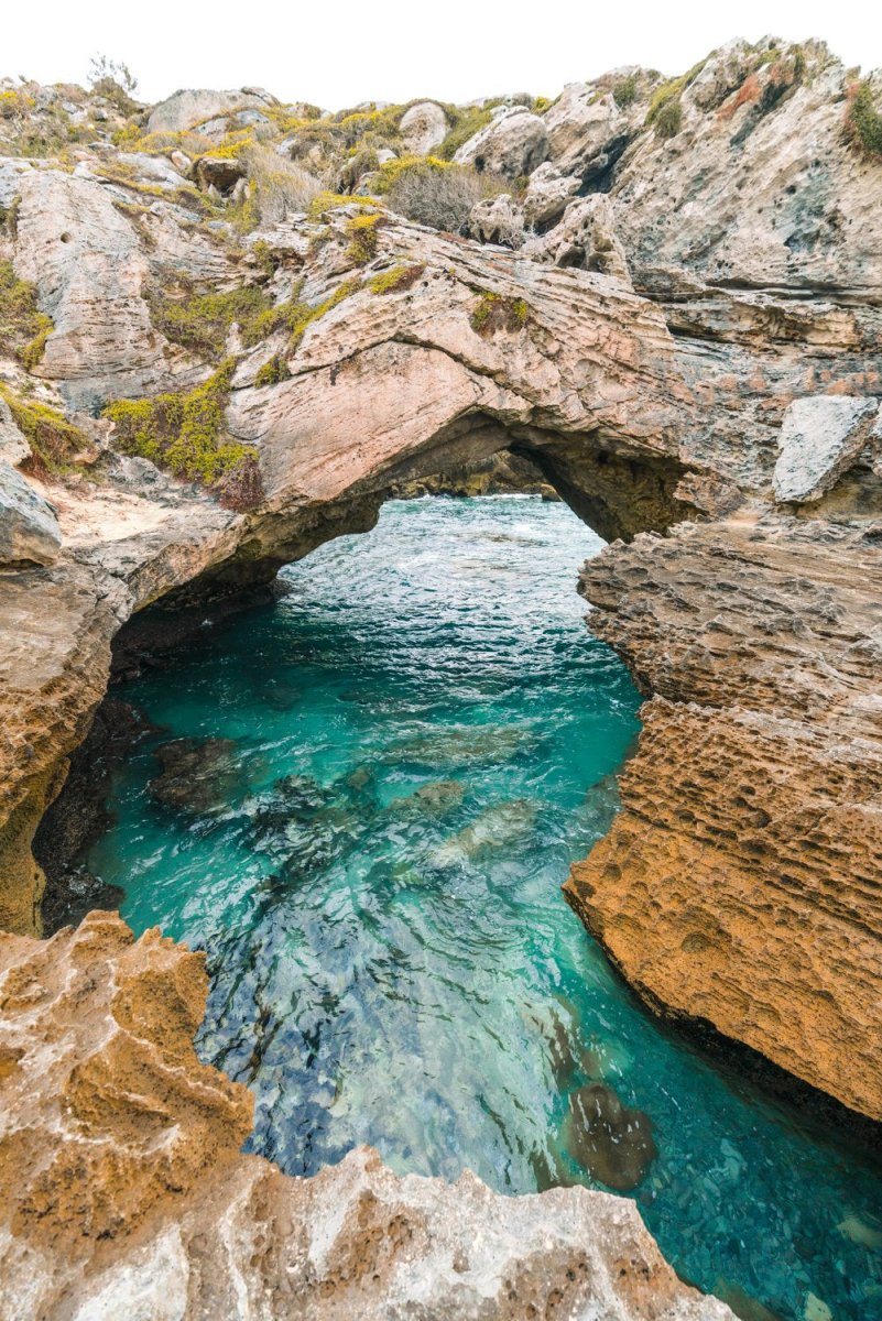 Turquoise water flowing through rock arch in arniston south africa