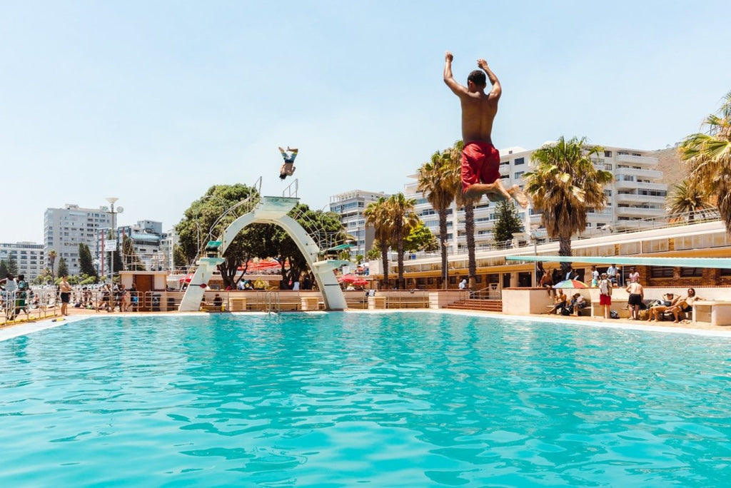 Two boys jumping in sea point pools during summer in cape town