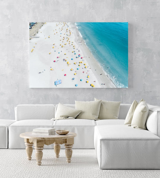 Aerial high above Camps Bay beach with lots of umbrellas and people in an acrylic/perspex frame