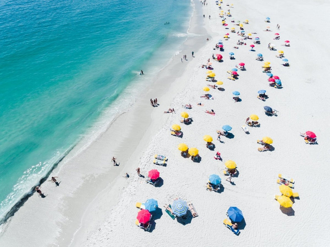 Aerial colorful umbrellas and people in sun on Camps Bay beach Cape Town