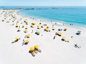 Aerial of yellow umbrellas, white sand and blue sea in Camps Bay Cape Town