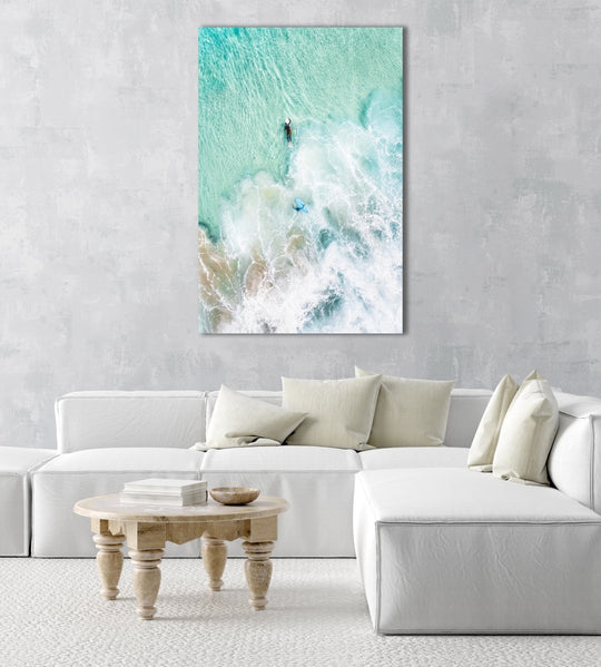 Aerial view of two surfers paddling in turquoise water and foam in a natural fine art frame