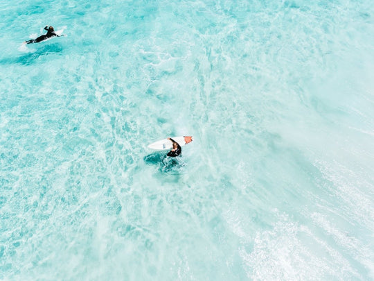 Surfers from above in light blue water in Cape Town