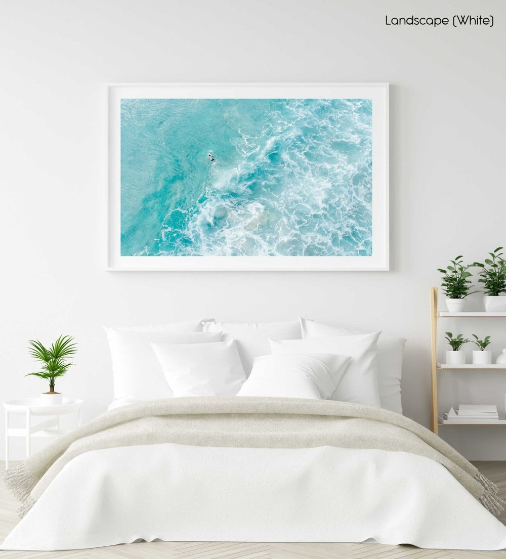 Light blue surfer paddling through foam from above in a white fine art frame