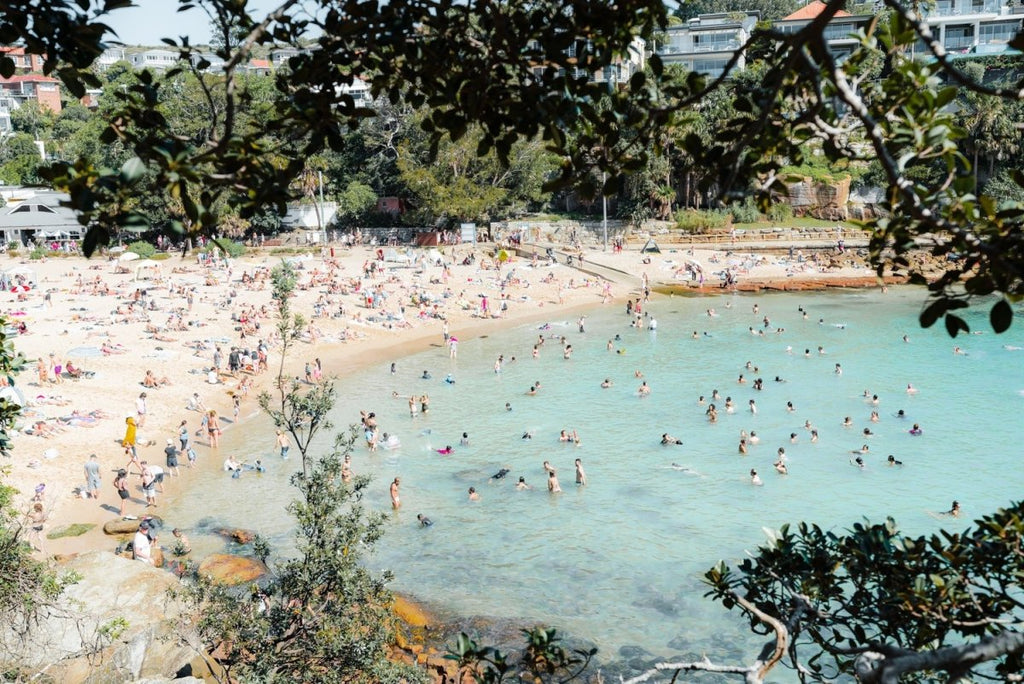Crowded Shelly Beach swimmers in turquoise water on summers day