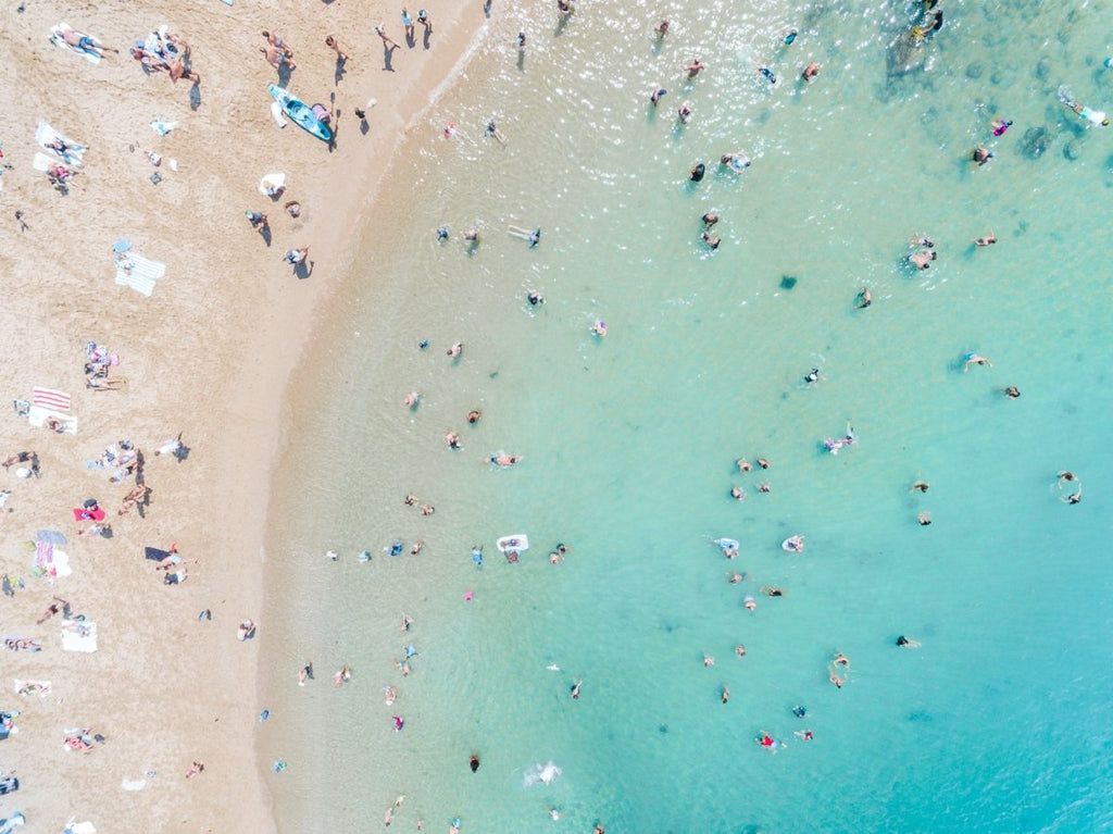 Aerial topdown of blue sea and people swimming at the beach in Sydney