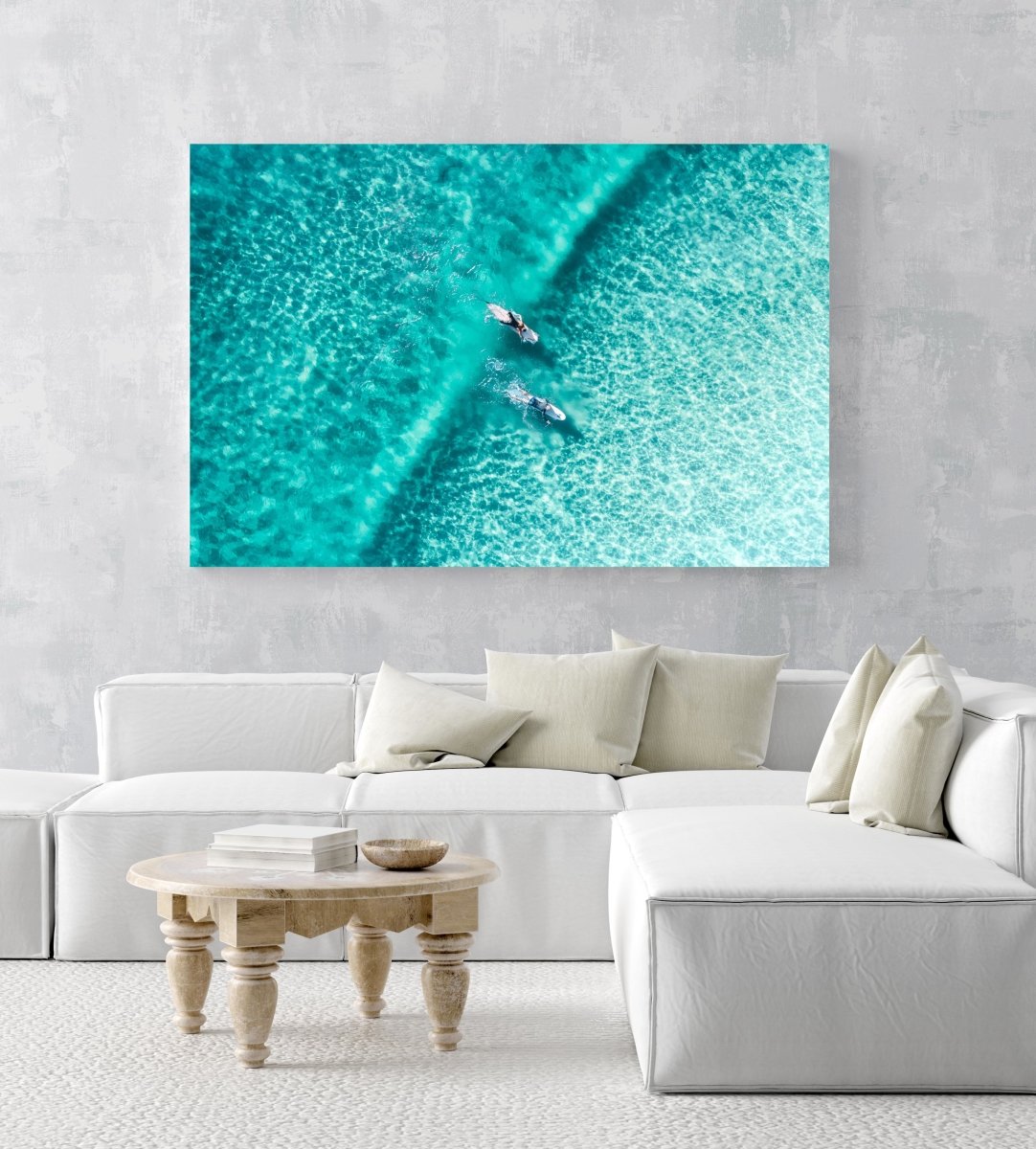 Two surfers paddling on one blue wave from aerial view in a white fine art frame