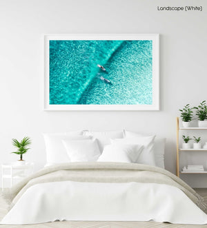 Two surfers paddling on one blue wave from aerial view in a white fine art frame