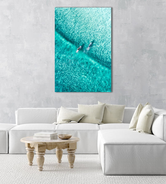 Two surfers paddling on one blue wave from aerial view in a natural fine art frame